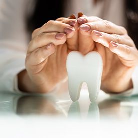 Woman’s hands placed over a tooth model