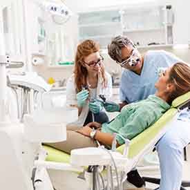 Dentist and dental assistant examining patient's teeth