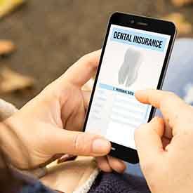 Patient reviewing dental insurance on phone outside