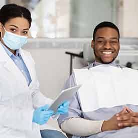 Dentist and patient smiling together in treatment room