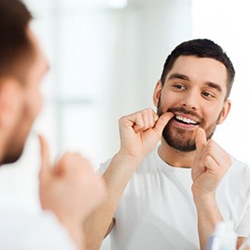 Closeup of man flossing his teeth in bathroom