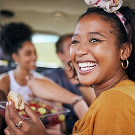 Woman smiling while eating lunch in car with friends