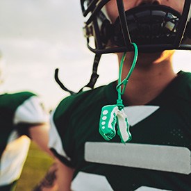 Green and white mouthguard hanging from helmet