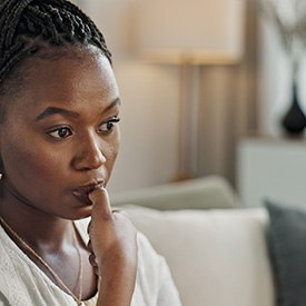 Closeup of woman biting her nails on couch at home