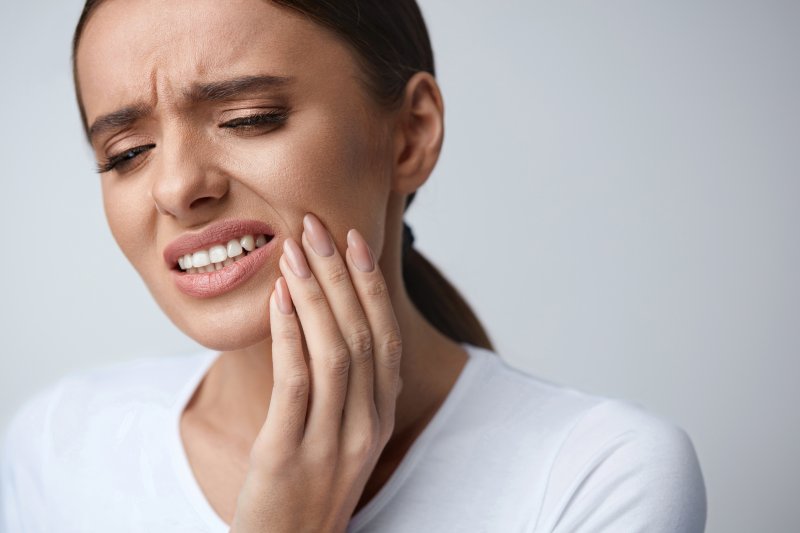 patient suffering from facial pain holding cheek